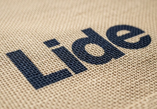 A close-up of a bold, one-color logo screen printed directly onto a jute bag.