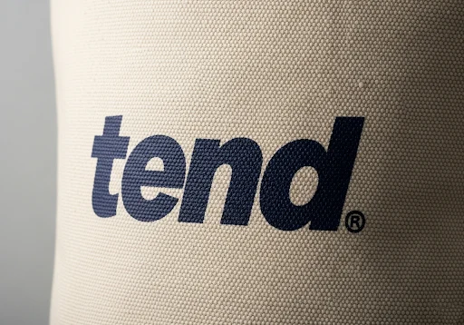 A close-up of a canvas bag with a bold, one-color logo applied via screen printing.