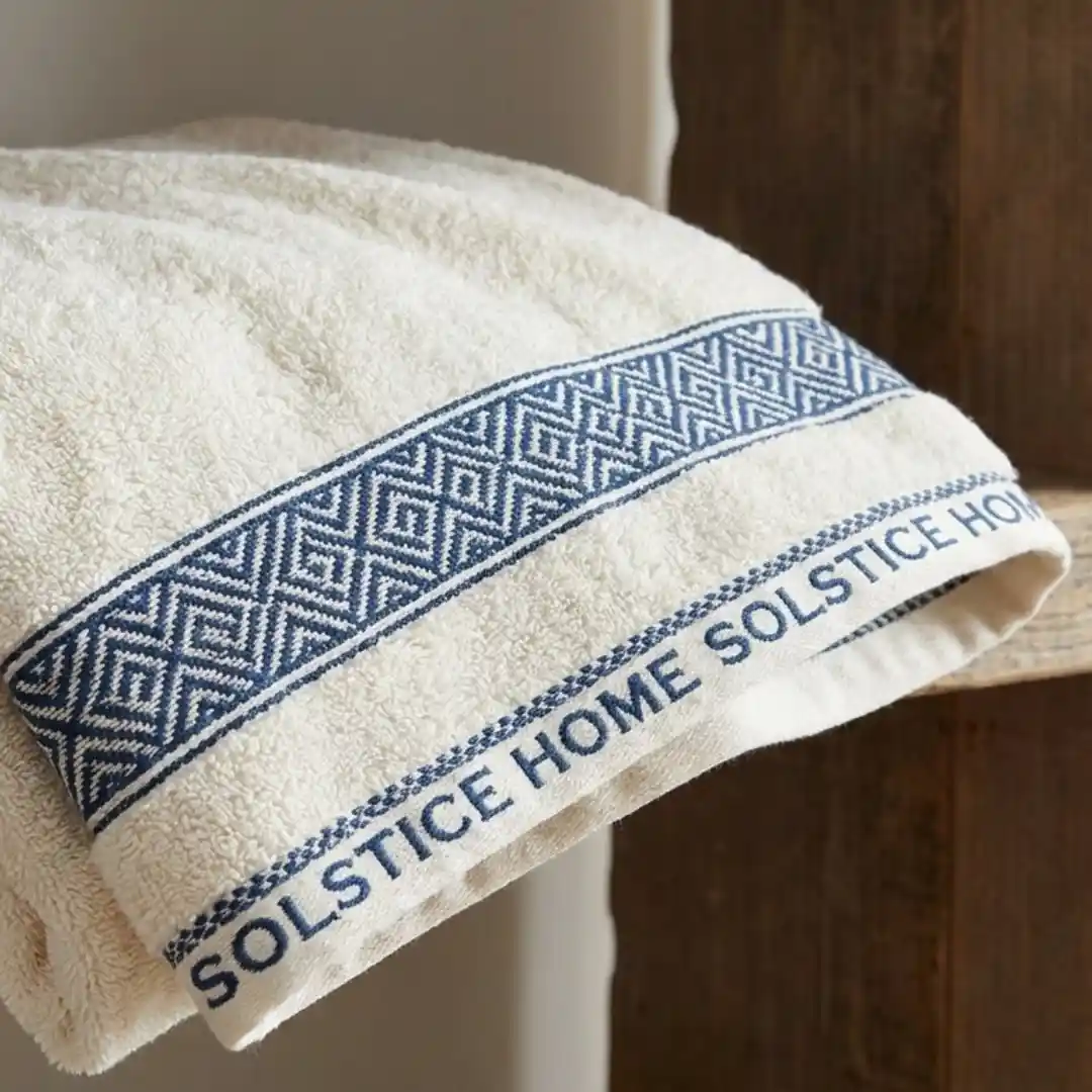 A cotton towel featuring a custom woven dobby border with a brand name.