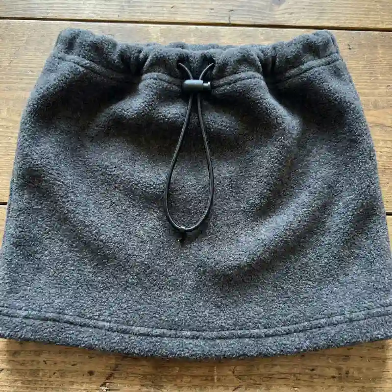 Fleece neck gaiter with an adjustable elastic drawstring and toggle.