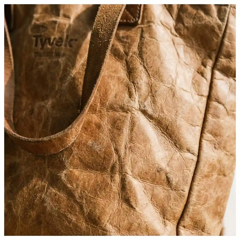 A close-up of a Tyvek tote bag showing its signature crumpled, paper-like texture that looks like aged leather.