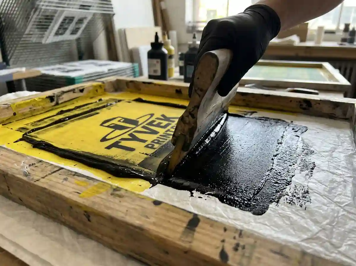 Silk screen printing setup applying white ink onto a flat cork fabric sheet.